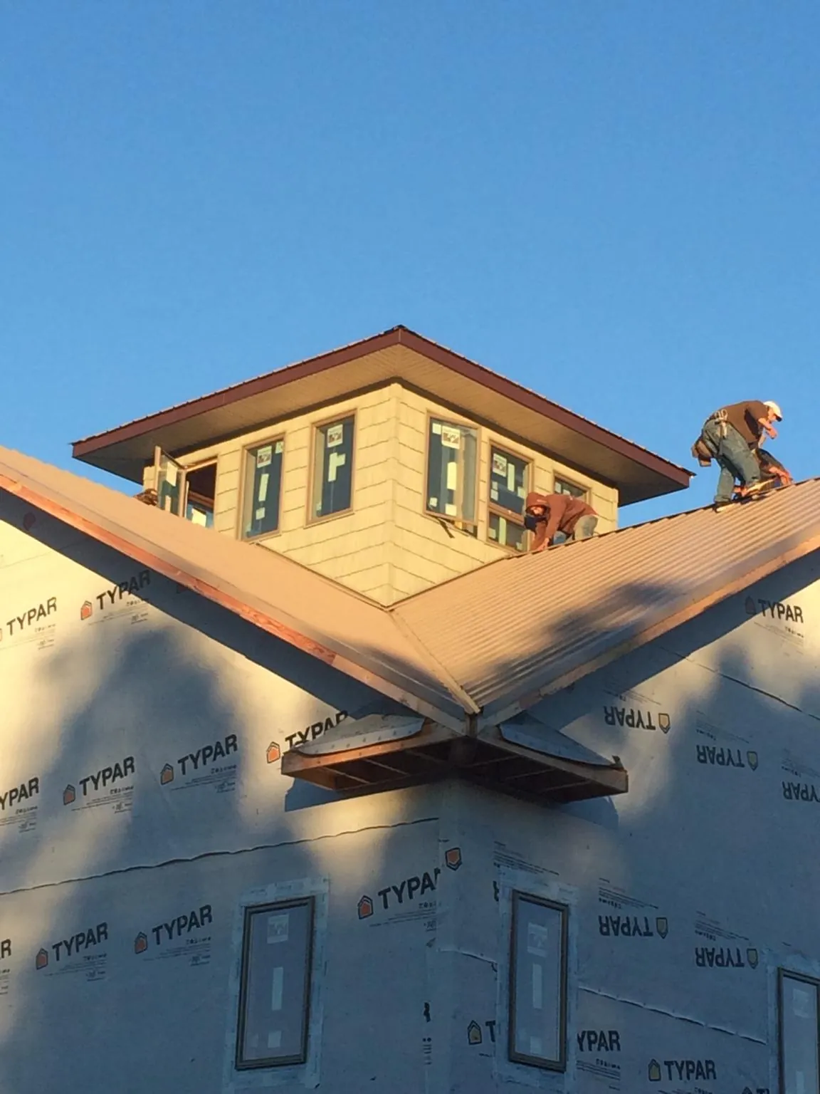 Roofers working around a rooftop cupola on a new metal roof at sunset — Roof Waterproofing in Faison by Roofing Brothers